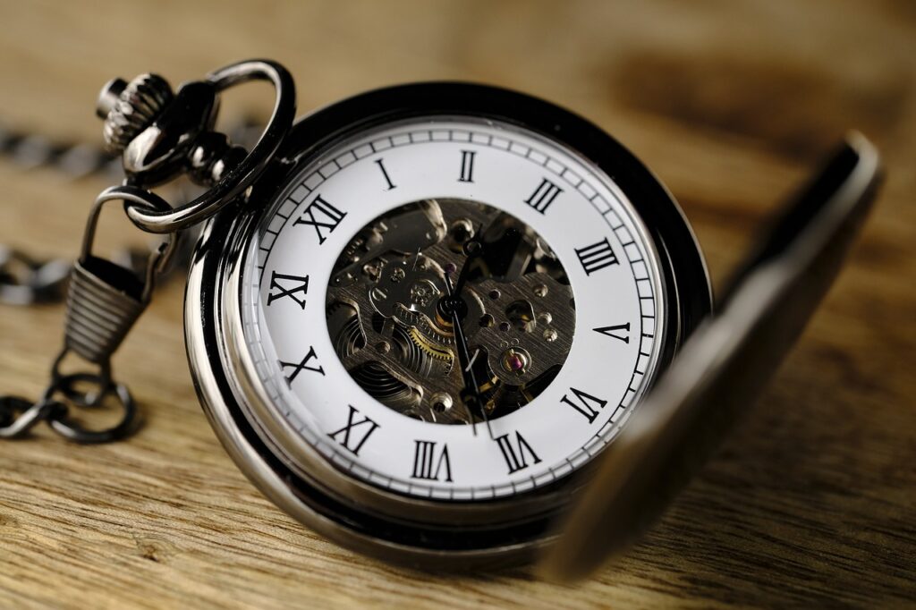 Close-up of a vintage mechanical pocket watch showing its inner gears and Roman numeral dial.