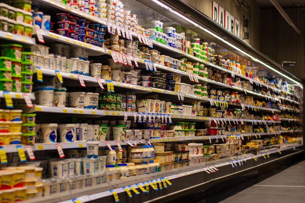 Fully stocked dairy aisle in a supermarket showcasing yogurt, milk, and other refrigerated products.