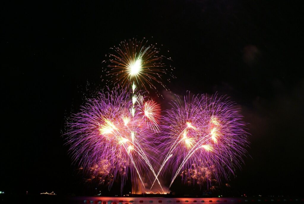 Colorful fireworks bursting in the night sky over a body of water during a celebration.