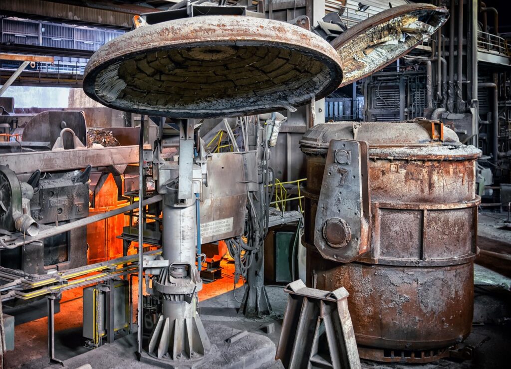 Industrial furnace and rusted equipment inside a heavy manufacturing facility.