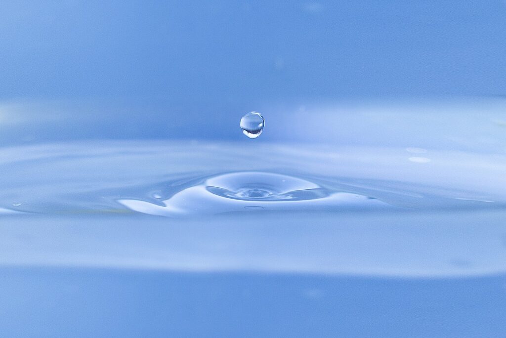 water droplet fliing into a blue field of water suggesting the idea of ultapure water