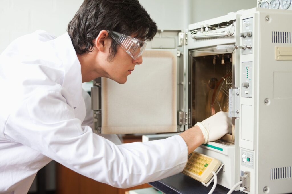 LAb worker placing item in laboraoty furnace for thermal analysis often a part of HALT Testing