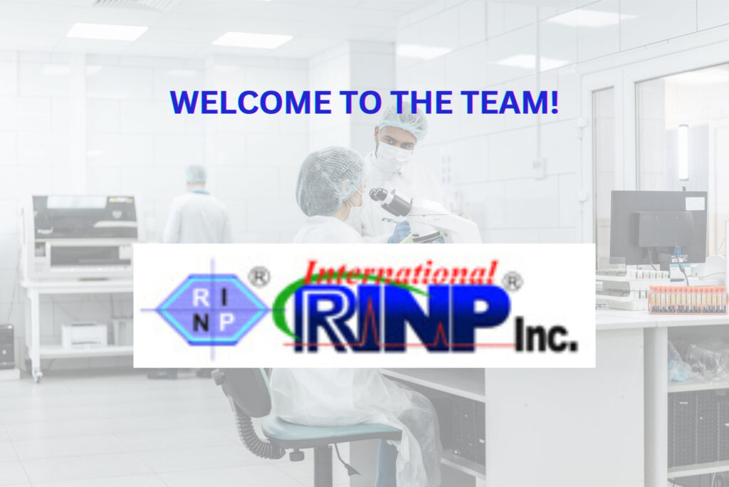 A male researcher in PPE discusses with a female researcher seated in front of a microscope. The brand logo of International RINP is in the foreground.