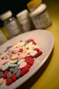 image ov a plate full of various tablets with pill bottles in teh background