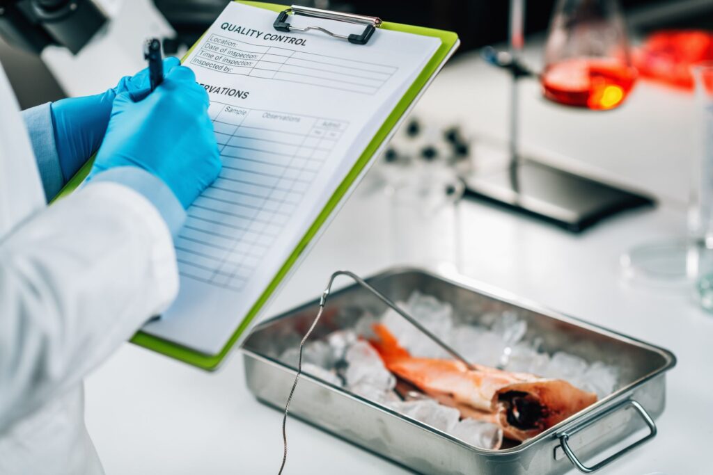 Food quality researcher with cliboard examining fish ilustrating the inportance of HACCP certification in food safety