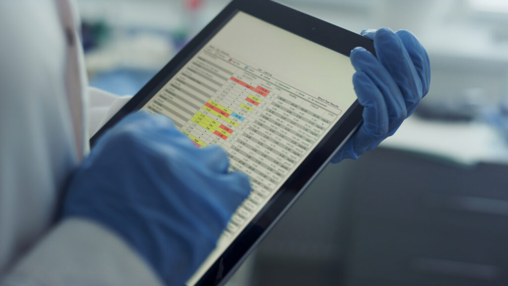 Gloved hands using tablet checking health history data in clinic office close up on a tablet screen. Modern technologies in hospital.