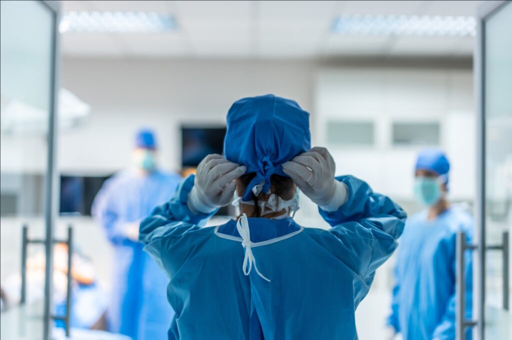 image of a surgeon entering an operating room and adjusting their PPE emphasizing the importance of mitigating microbial contamination risks i healthcare facilities
