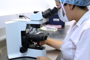Researcher working with a microscope in a flow cytometry lab