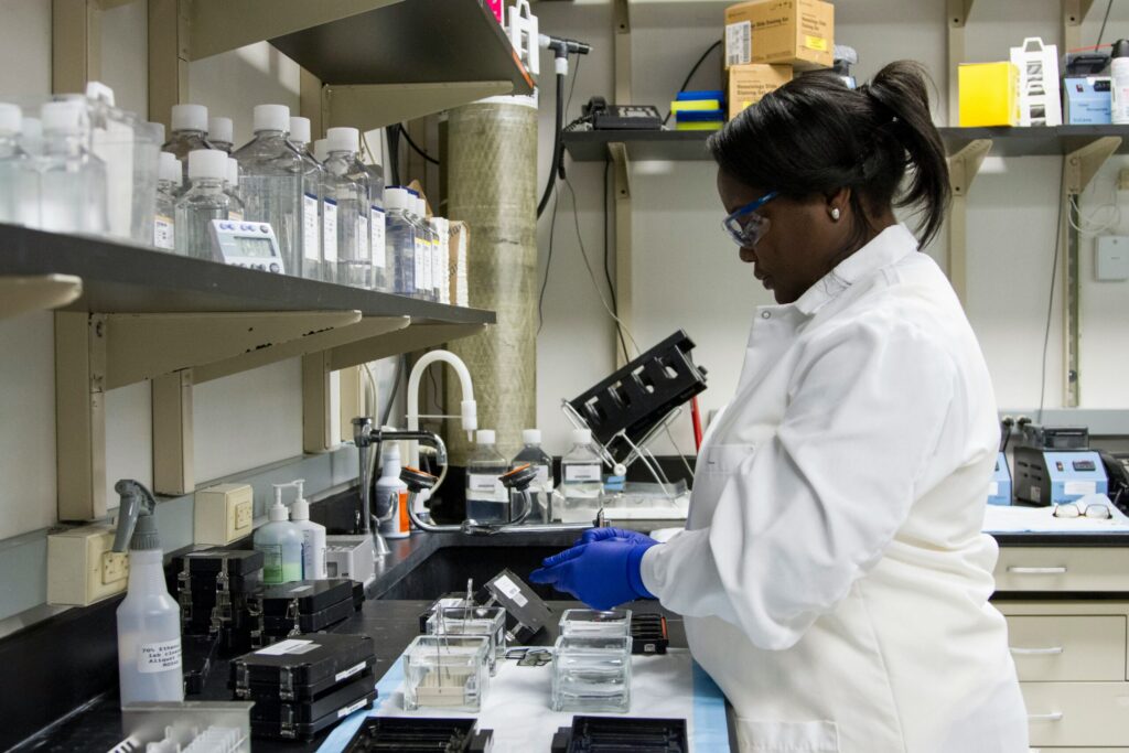A female researcher wearing lab coat and gloves working in a laboratory setting.