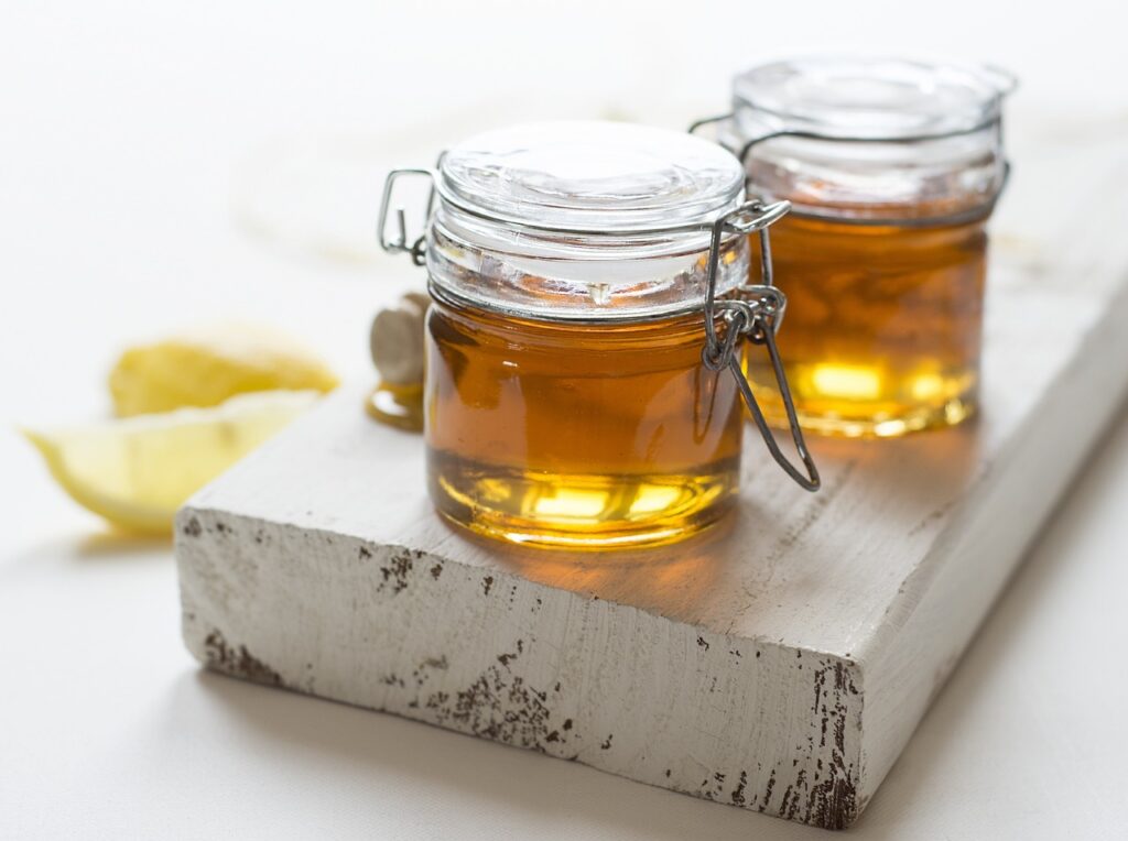 2 Jars of honey sitting on a white wooden board