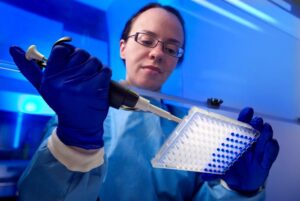 Female researcher performing Quantitative Polymerase Chain Reaction qPCR Analysis in a biological safety cabinet