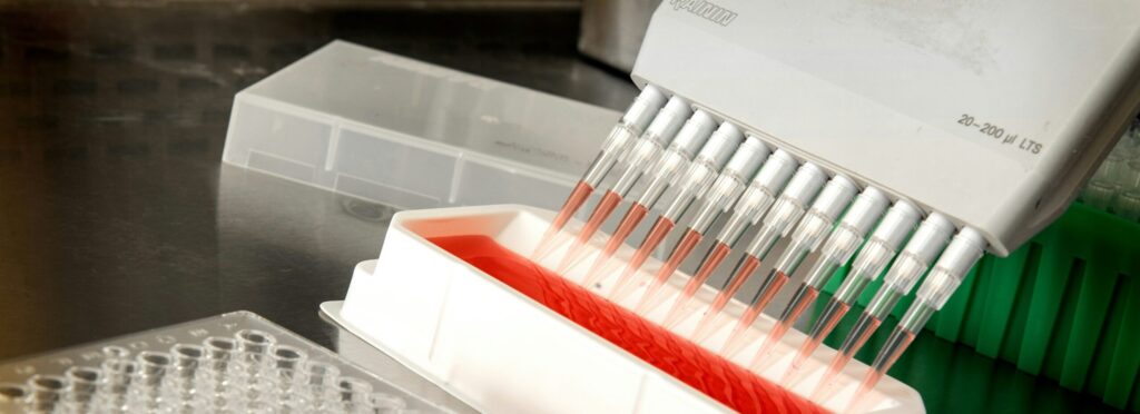 A multi-channel micropipette with filter tips aspirating liquid from a container.