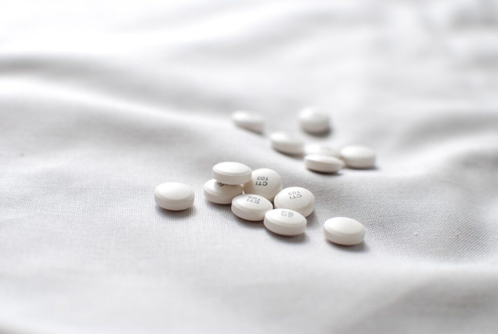 White tablets scattered on a soft, white fabric surface in natural light.